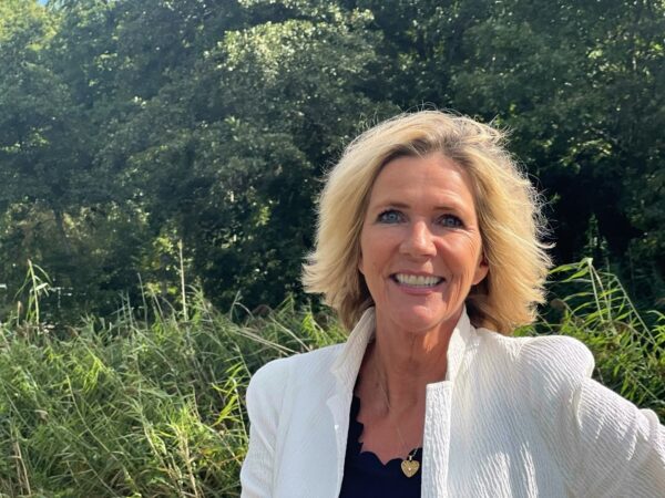 Smiling person in nature with greenery background.