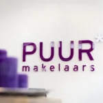 The logo of “PUUR makelaars” in bold purple letters with an asterisk symbol, set against a blurred background with matching purple tones, representing the company’s corporate identity.