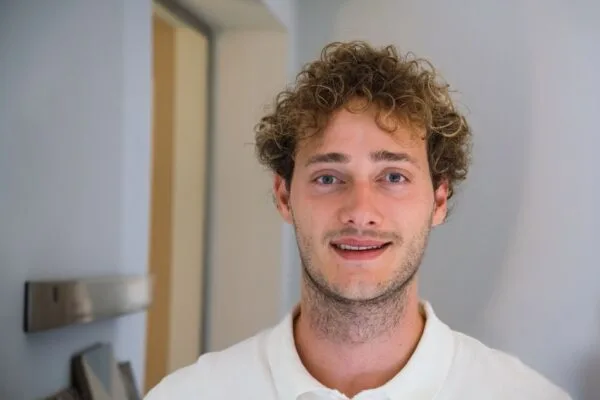 Smiling person with curly hair indoors