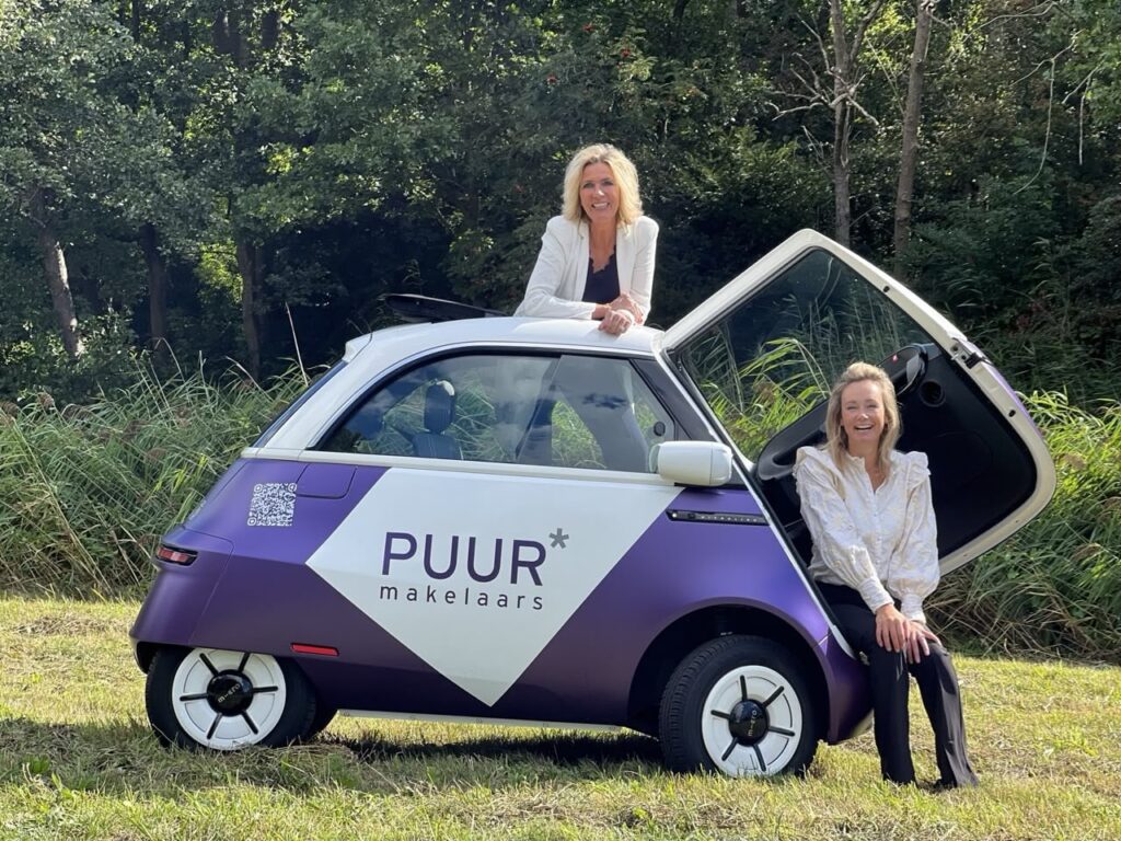 Two women with purple microcar in nature.