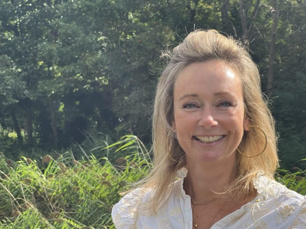 Smiling woman in white blouse outdoors.