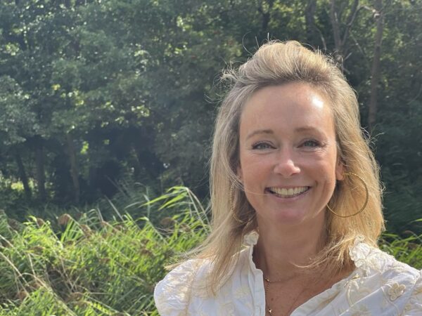 Smiling woman in white blouse outdoors.