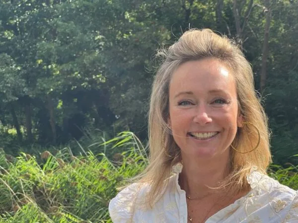 Smiling woman in white blouse outdoors.