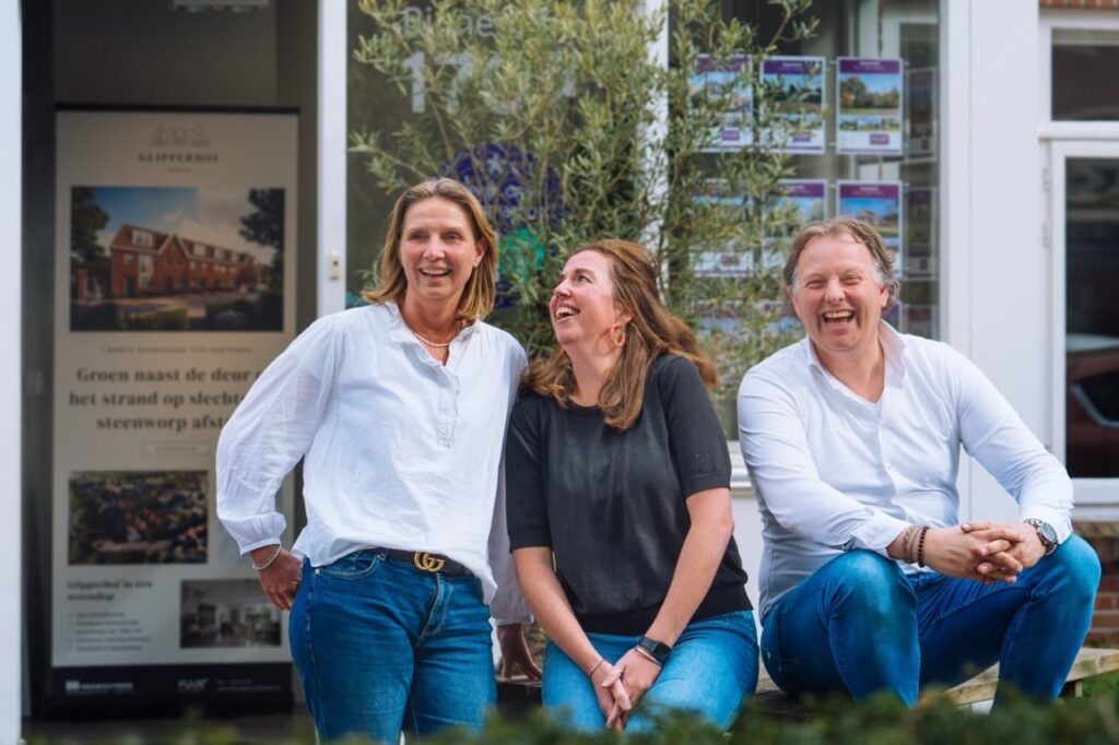 Three people laughing outside a building.
