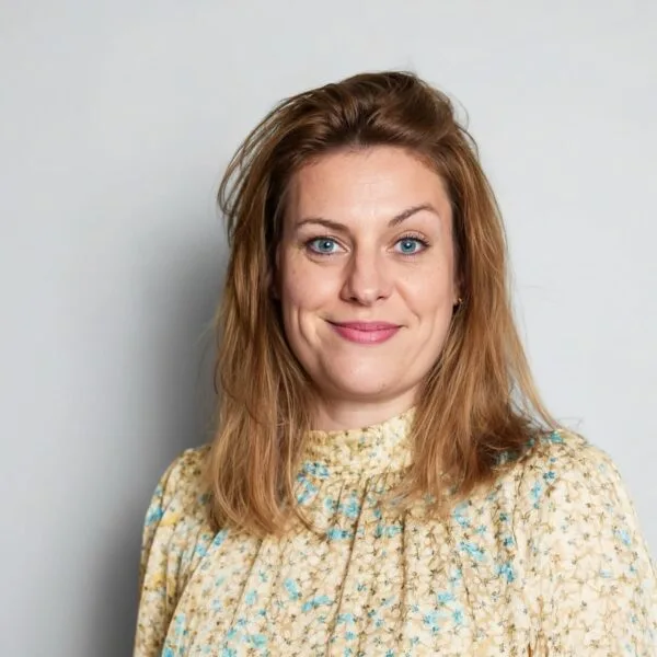 Smiling person in floral blouse with light background.