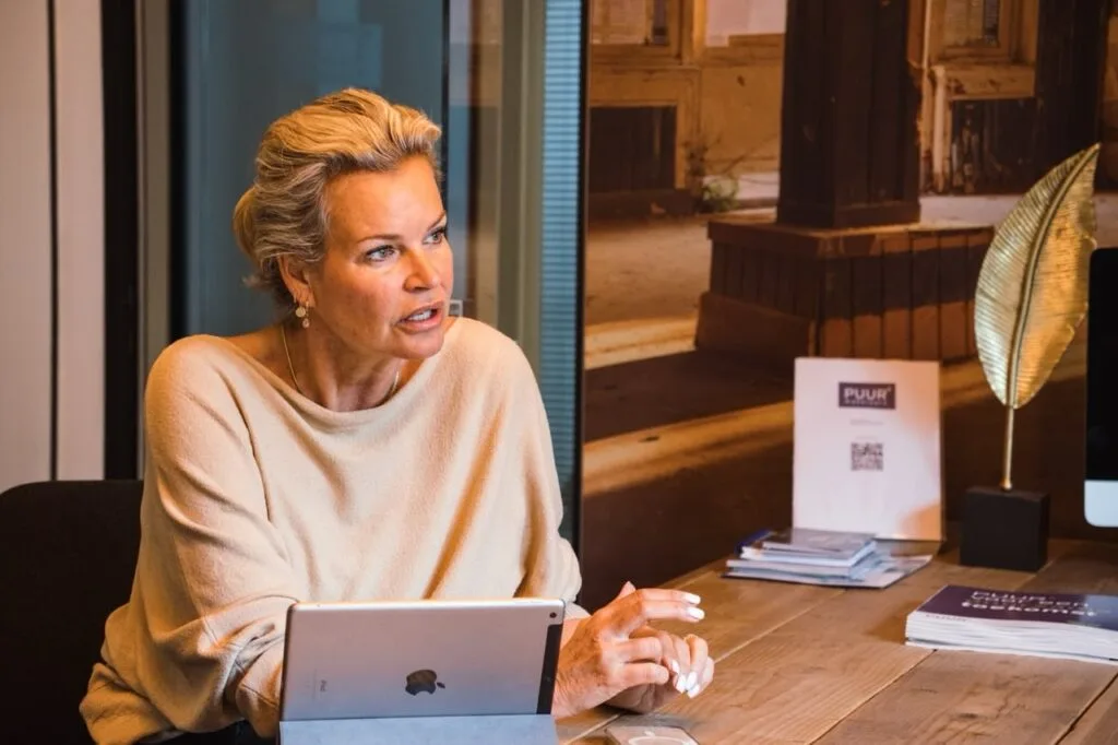 Woman speaking at a desk with tablet