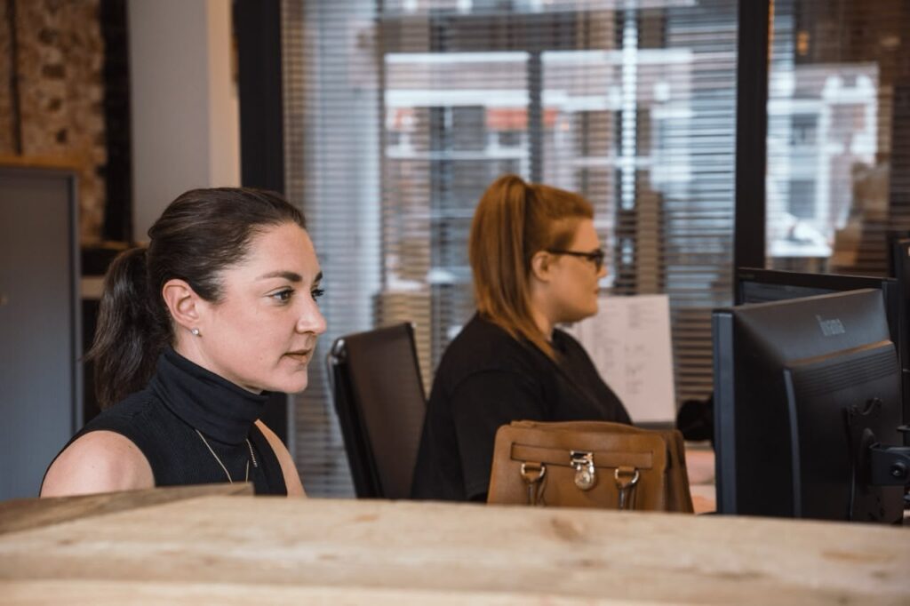 Women working at computers in office setting.