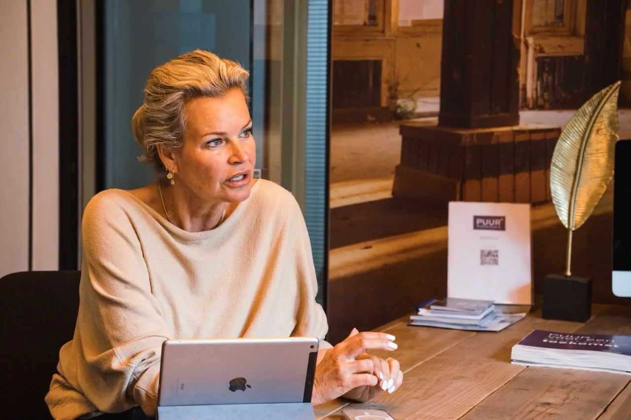 Woman speaking at a desk with tablet