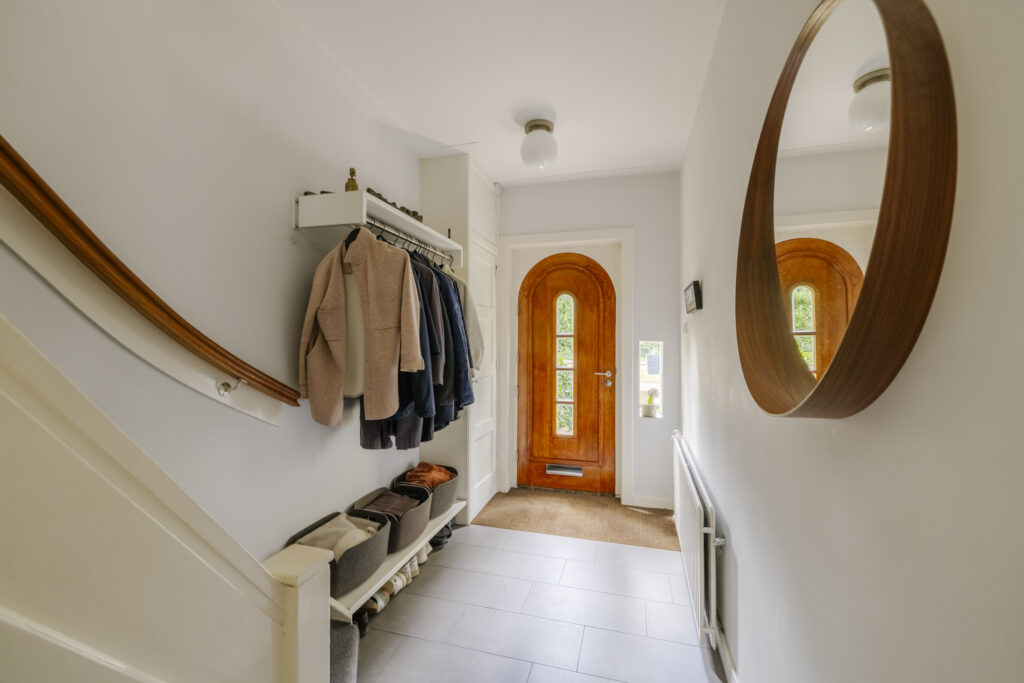 Bright hallway with coats, mirror, wooden door