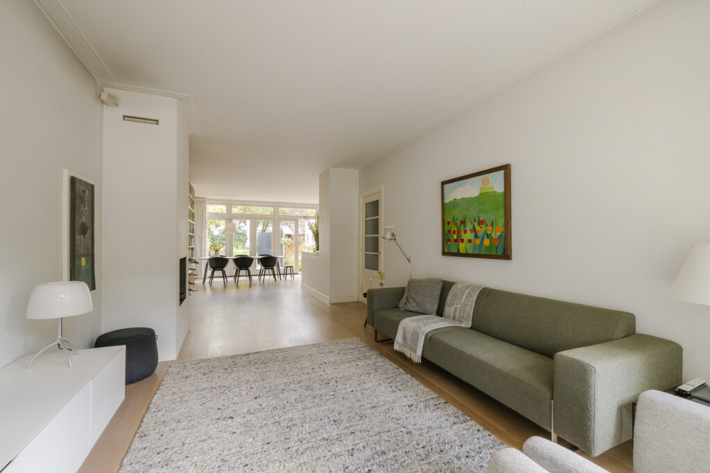 Spacious modern living room with green couch and art.