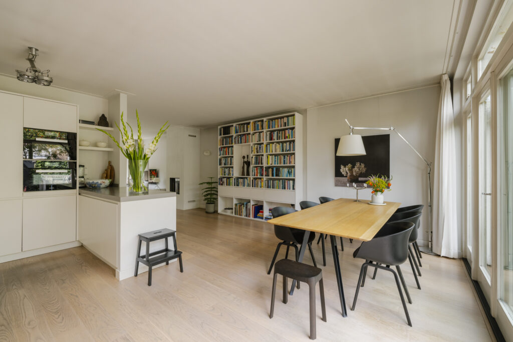 Modern dining room with bookshelves and large window.