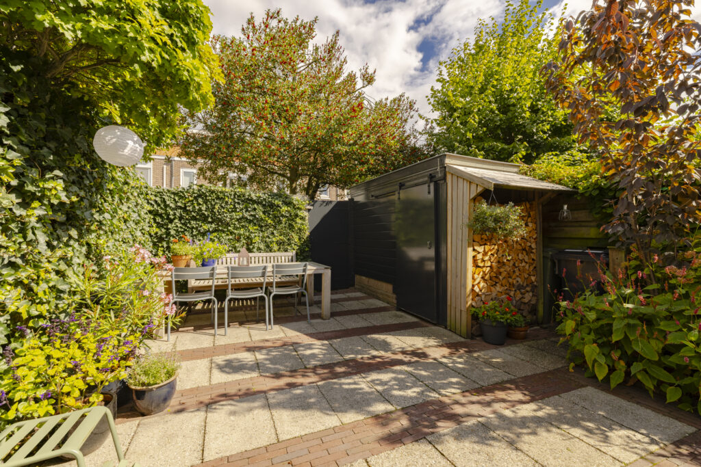 Sunny garden patio with shed and outdoor table.