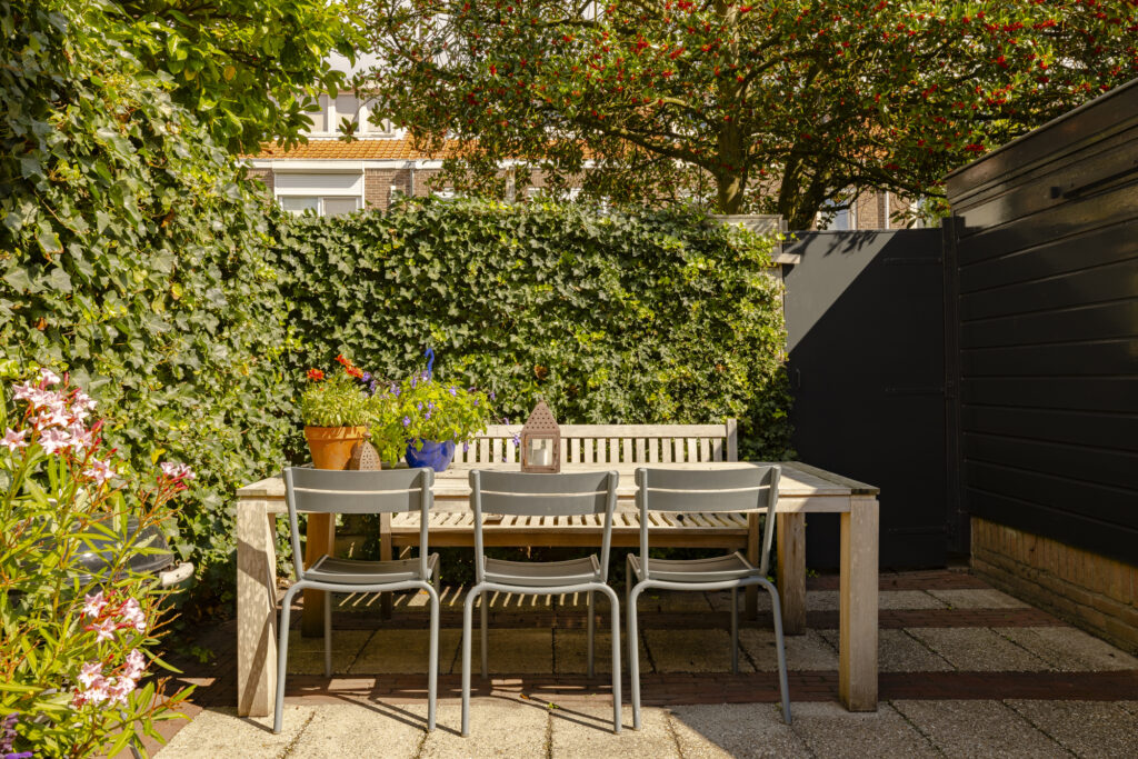 Cozy outdoor patio with wooden furniture and plants.