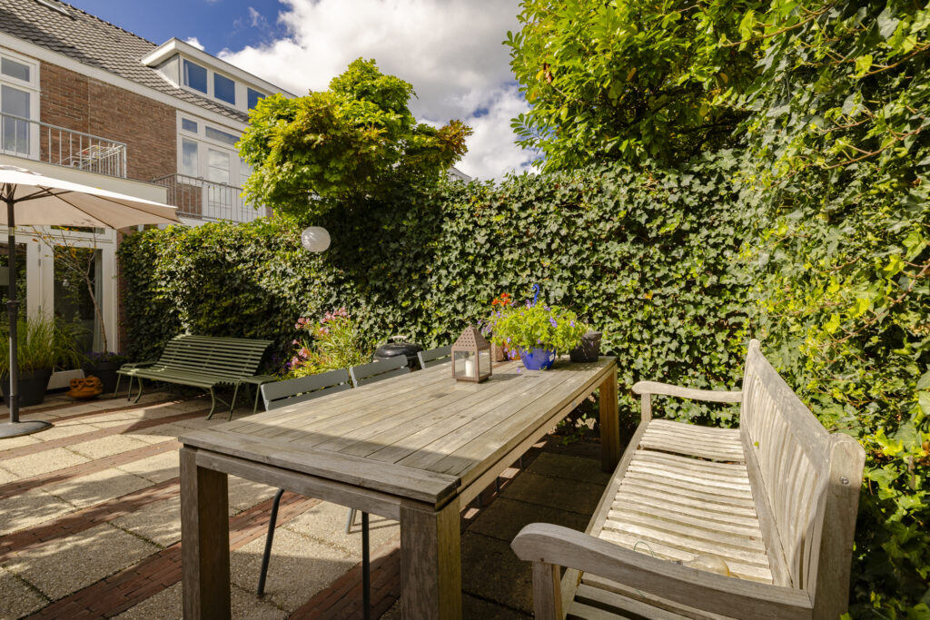 Sunny garden patio with wooden table and plants.