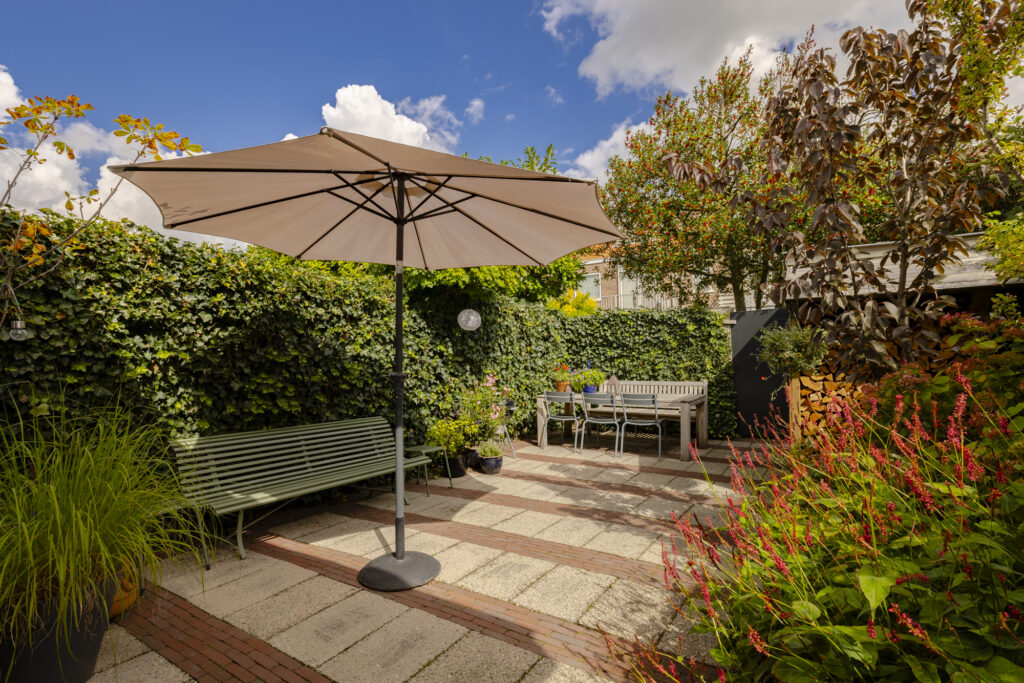 Sunny garden patio with umbrella and seating area.