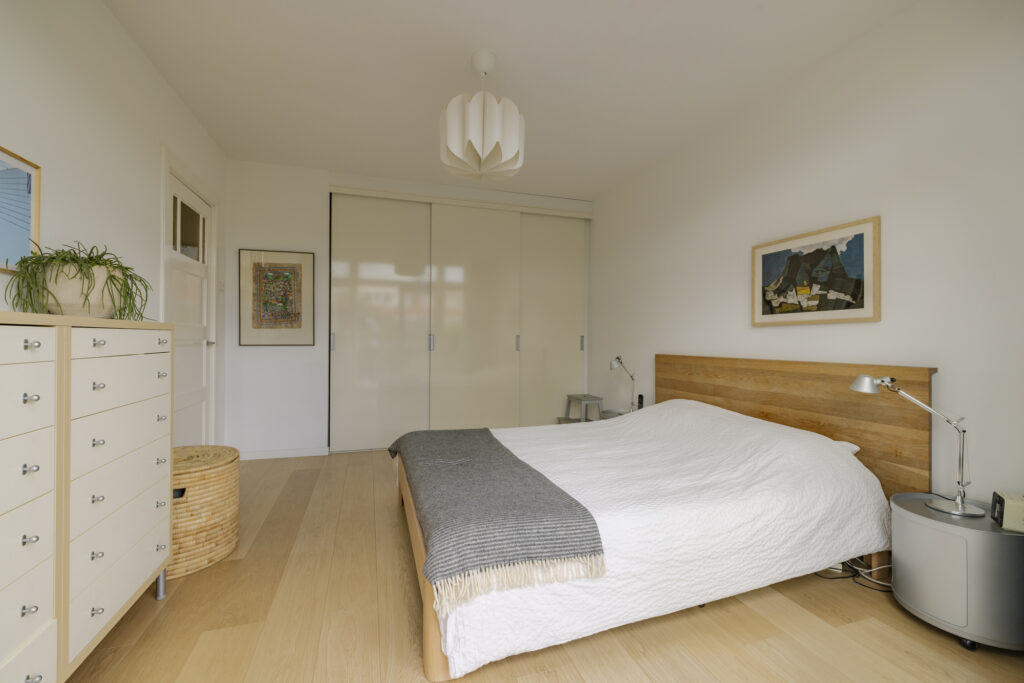 Minimalist bedroom with wooden bed and dresser.