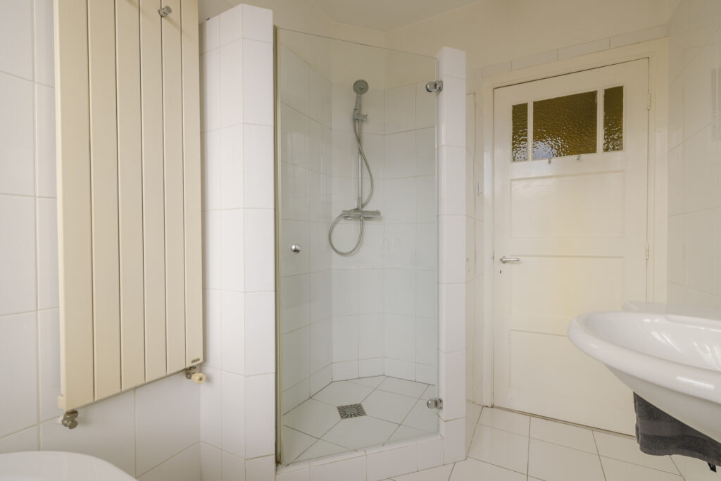 Modern bathroom with glass shower and white tiles.