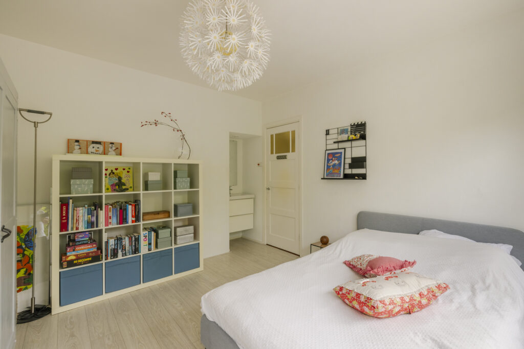 Cozy bedroom with bookshelf and modern decor.