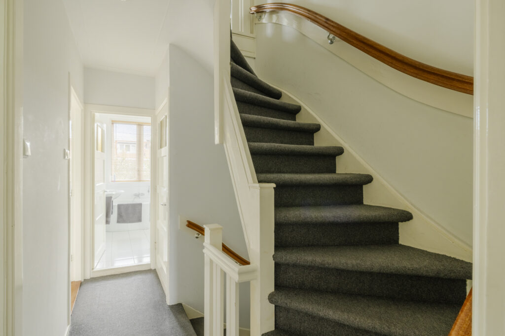 Carpeted staircase leading to bright hallway