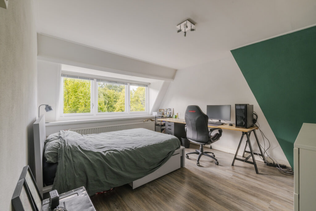 Modern bedroom with desk and large window.