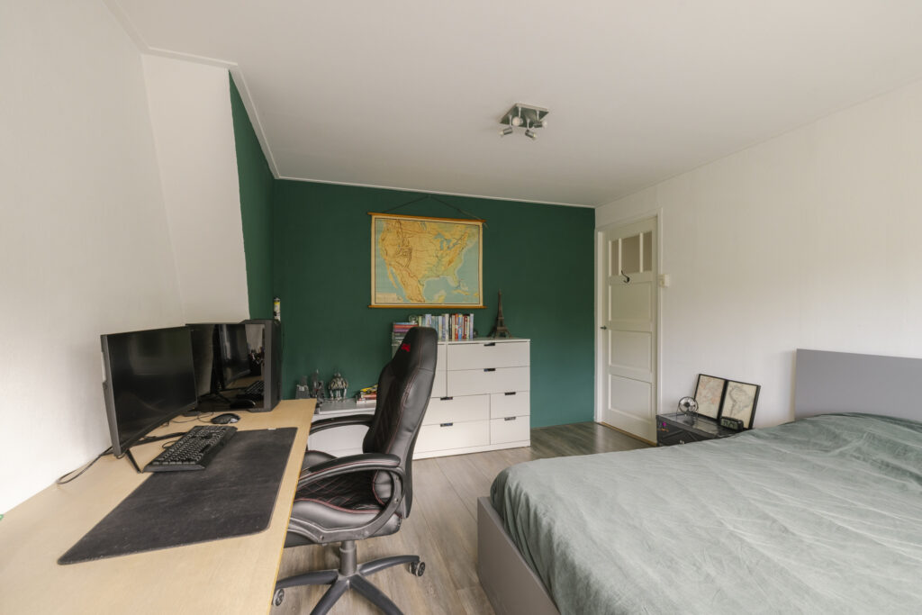 Cozy bedroom with desk, chair, and green wall.