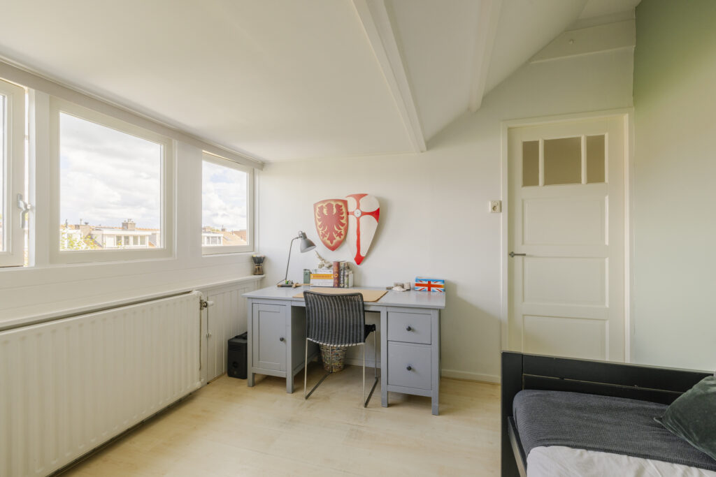 Bright room with desk and shields on wall.