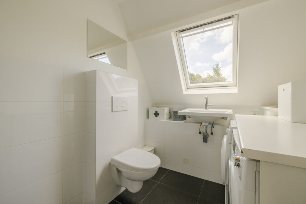 Modern bathroom with skylight and white fixtures.