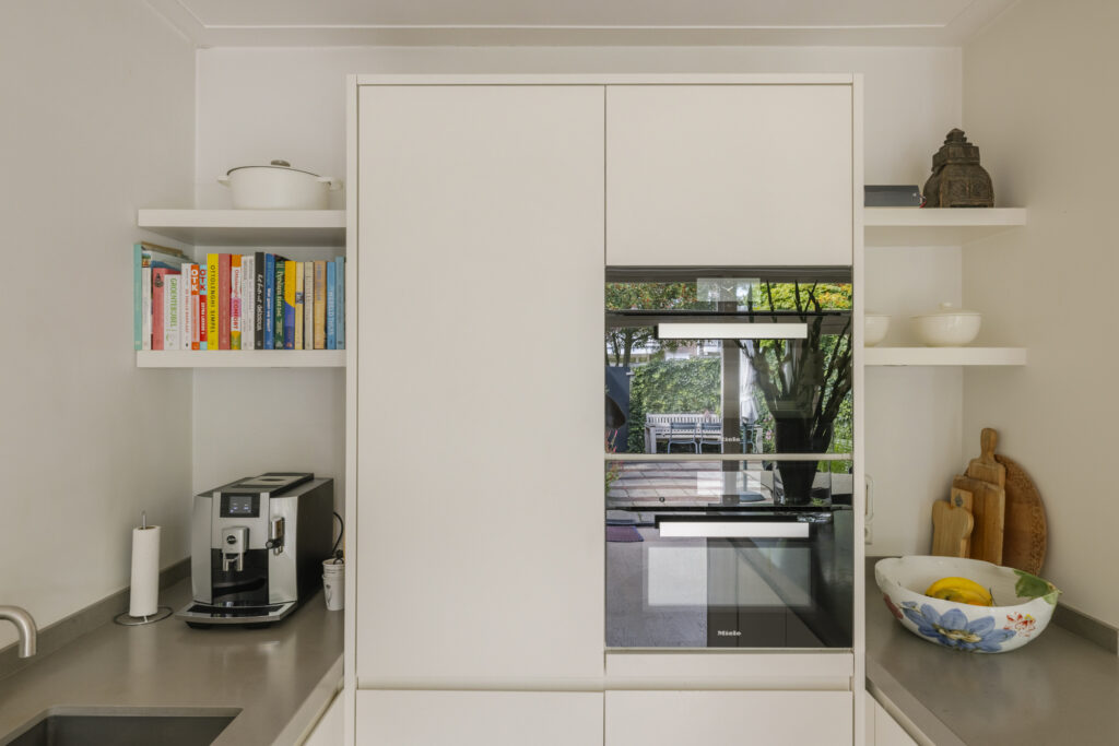 Modern kitchen with shelves, books, and coffee machine.