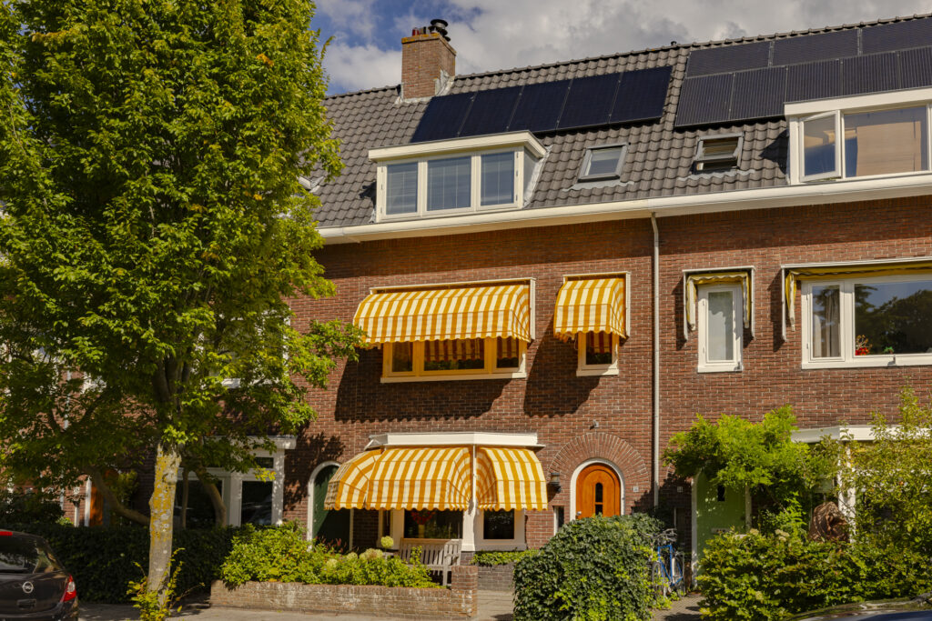 Brick house with yellow striped awnings and solar panels.