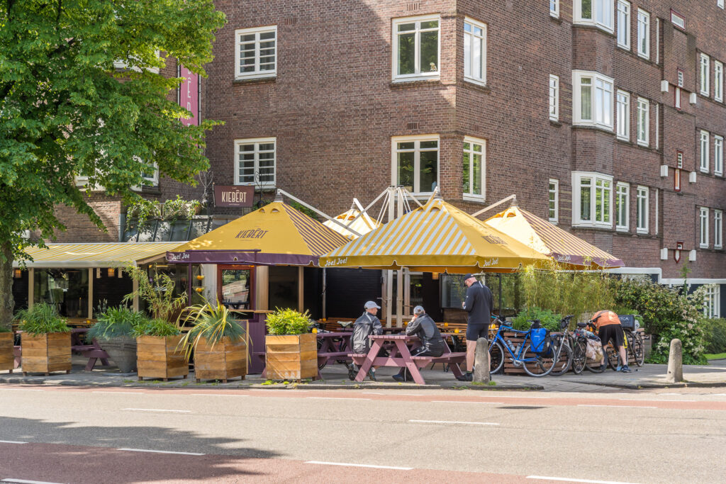 Bicyclists at outdoor cafe with yellow umbrellas.