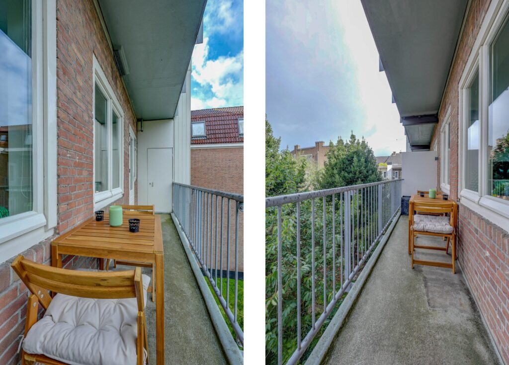 Narrow balcony with chairs and wooden table.