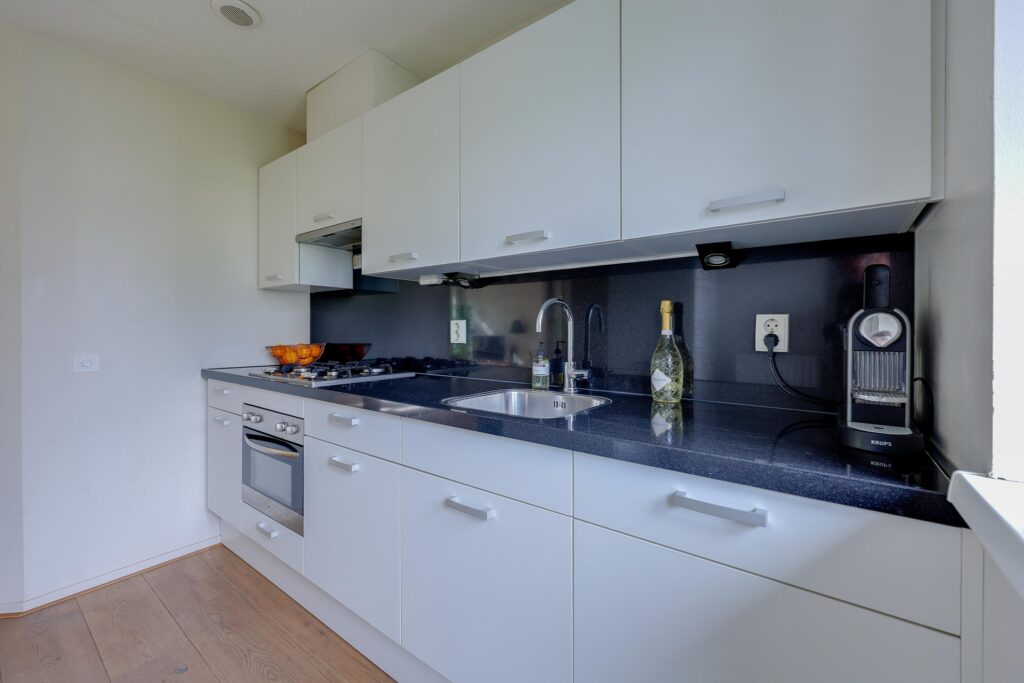 Modern kitchen with appliances and sleek white cabinets.