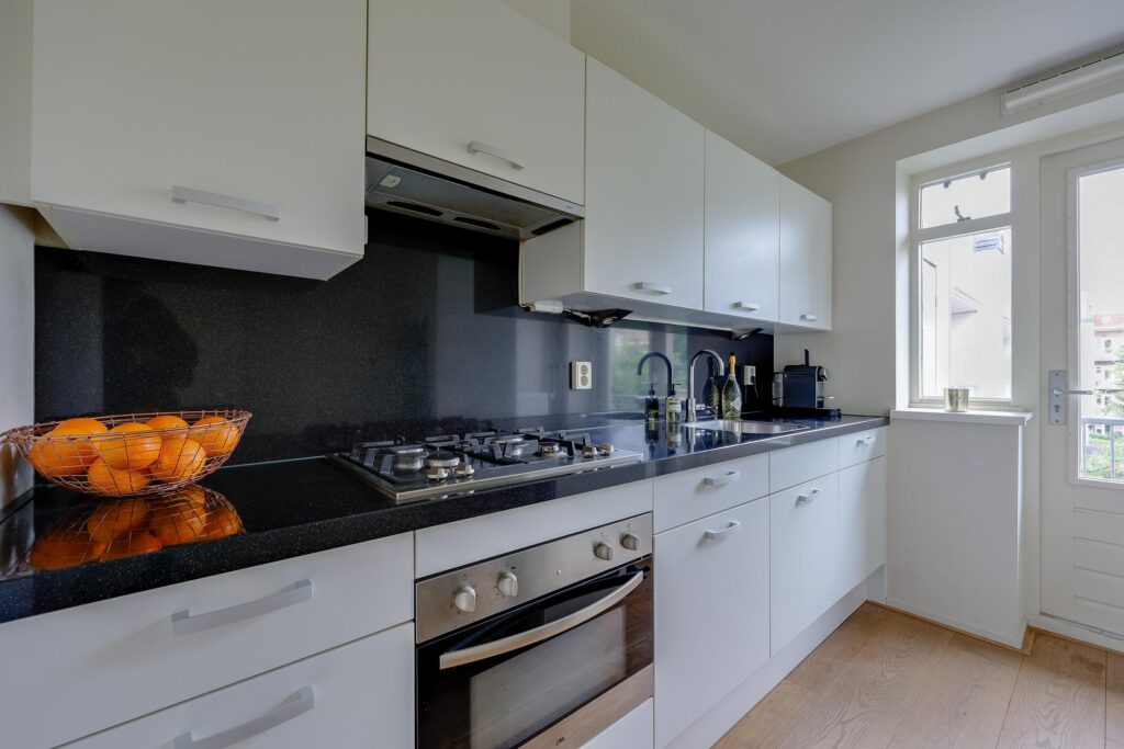 Modern kitchen with white cabinets and black countertop.