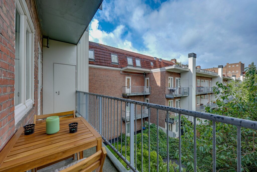 Balcony view of brick apartment buildings and greenery.
