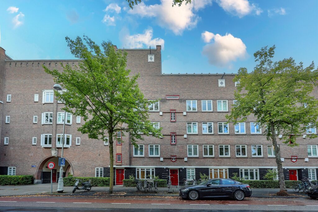 Brick apartment building with trees and parked car