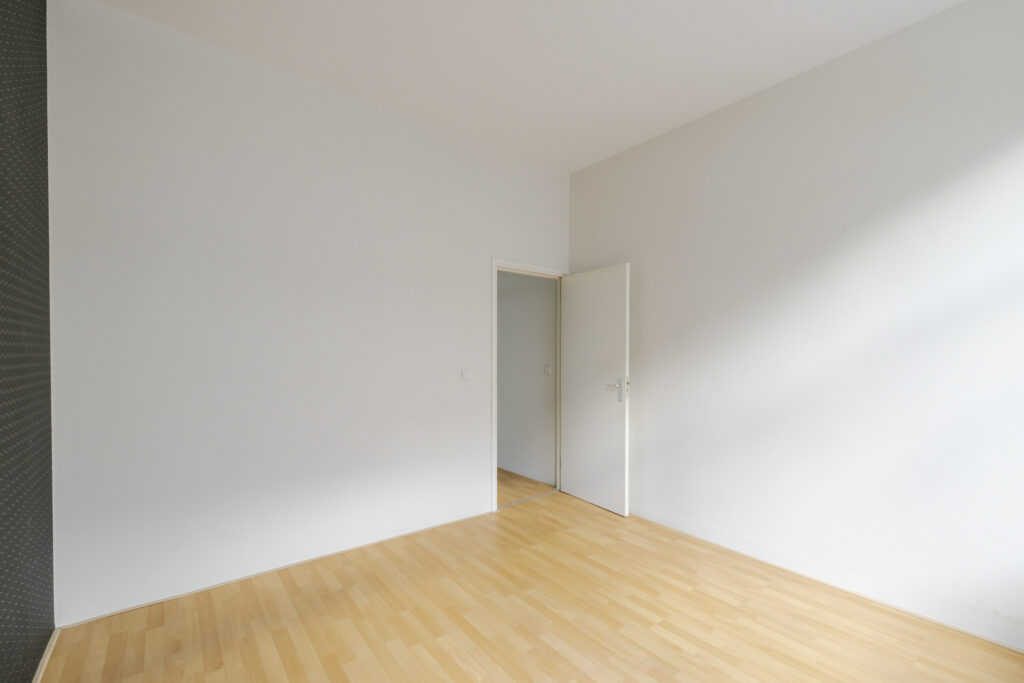 Minimalist empty room with wooden floor and door.