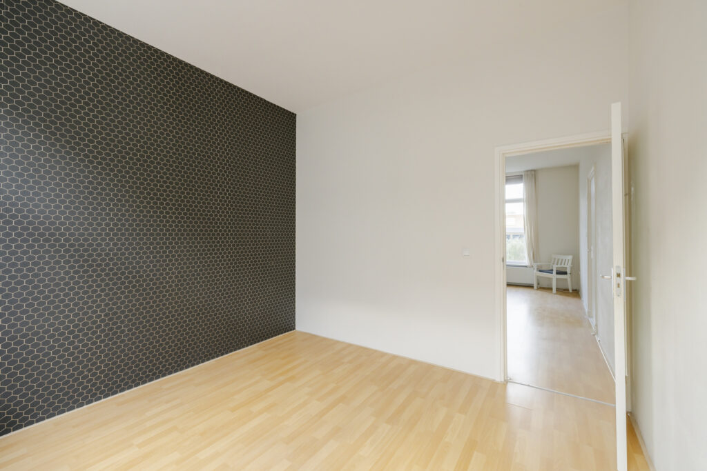 Empty room with patterned accent wall and window.