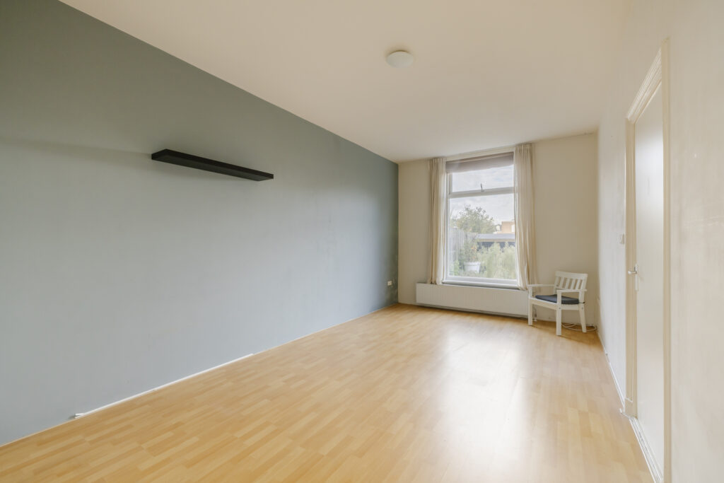 Empty room with wooden floor and window view.