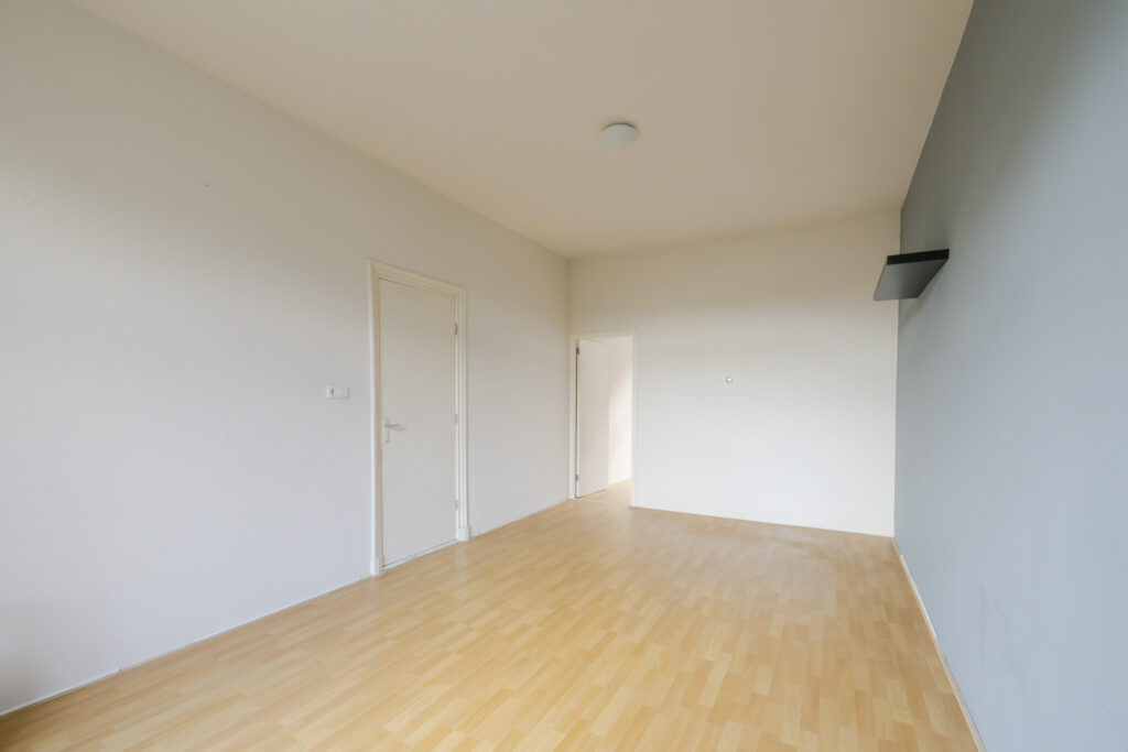 Empty room with wooden floor and gray walls.