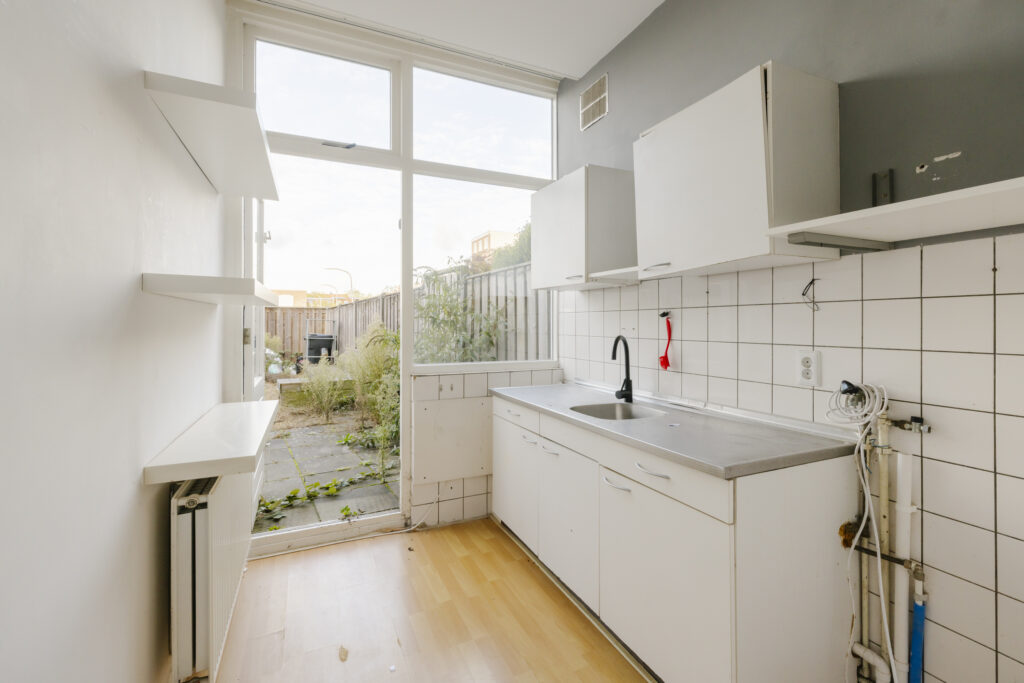 Empty kitchen with tiled backsplash and patio door.