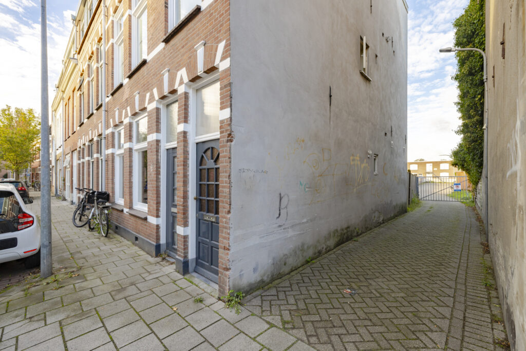 Narrow alley between brick townhouses with street art.