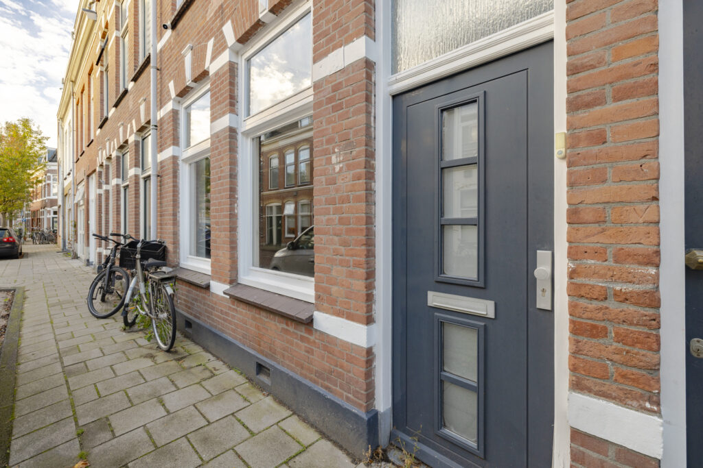 Brick facade with bicycles by blue door.