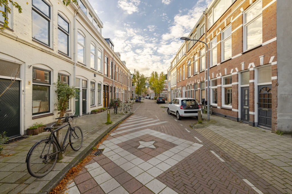 Quiet residential street with bicycles and cars parked.