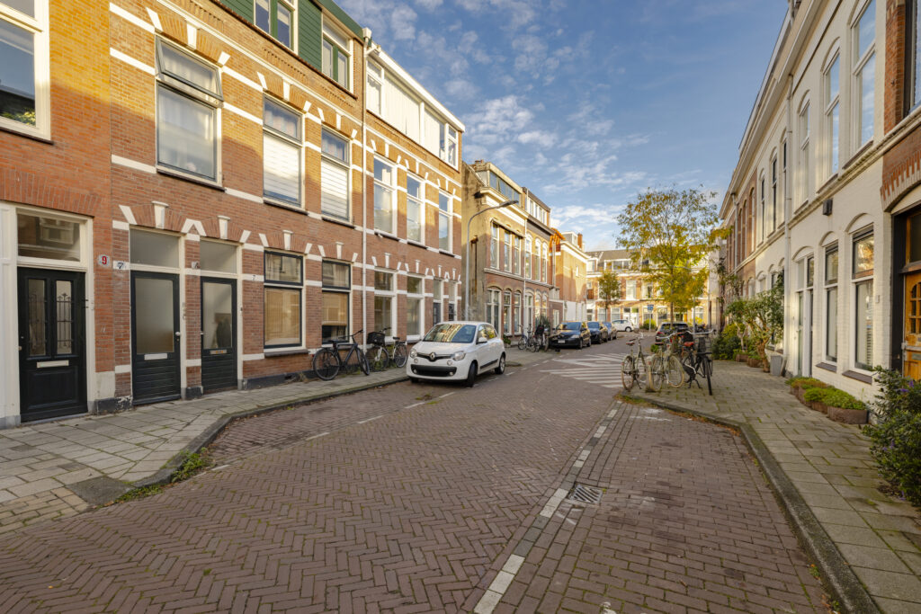 Quiet European street with parked cars and bicycles.