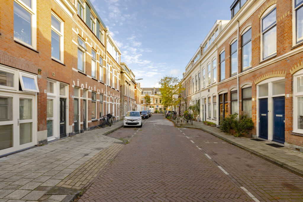 Quiet residential street with parked cars and bicycles.