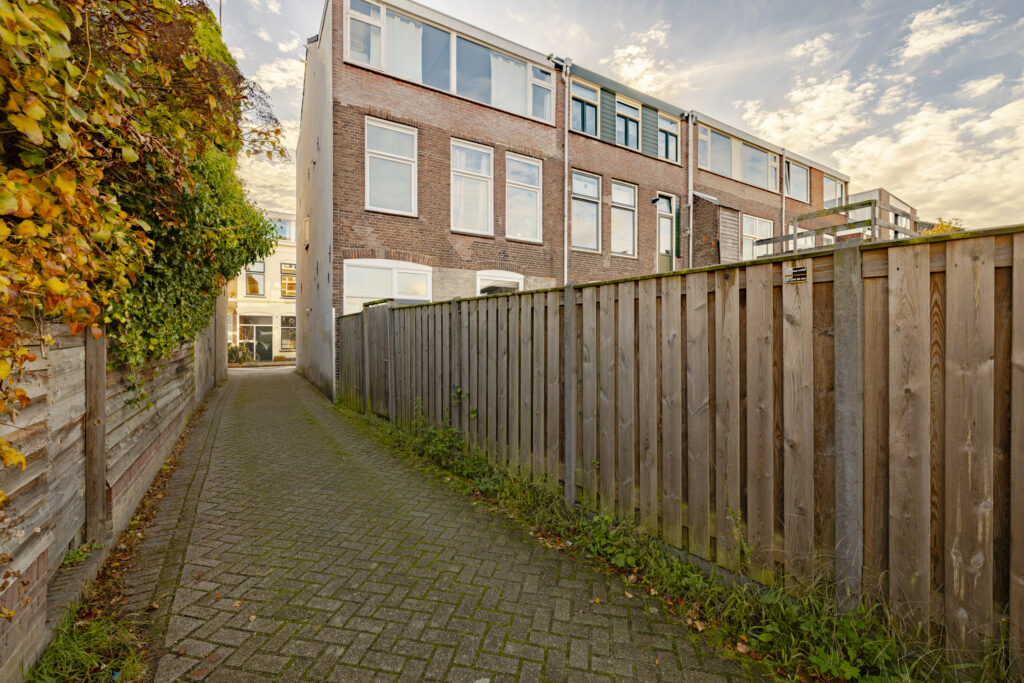 Brick alleyway with wooden fences and autumn leaves.