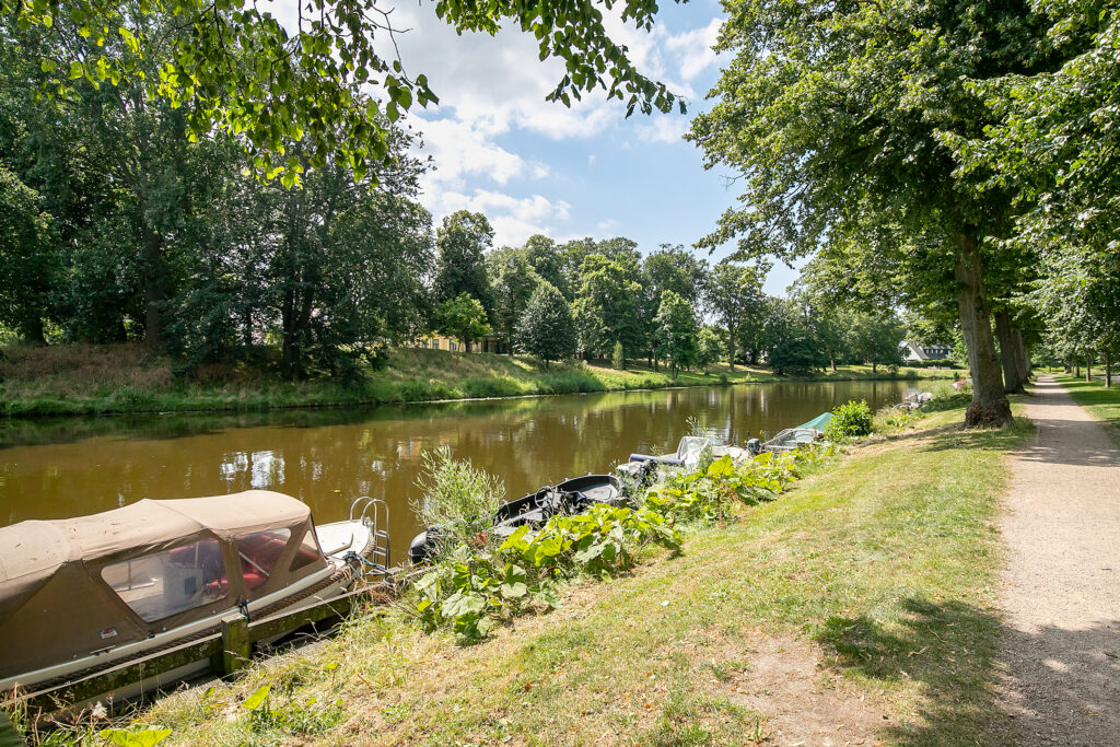 Boats docked along peaceful riverside path.