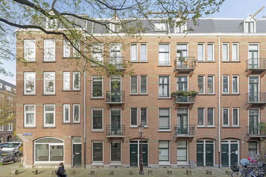 Brick apartment building with balconies and windows.