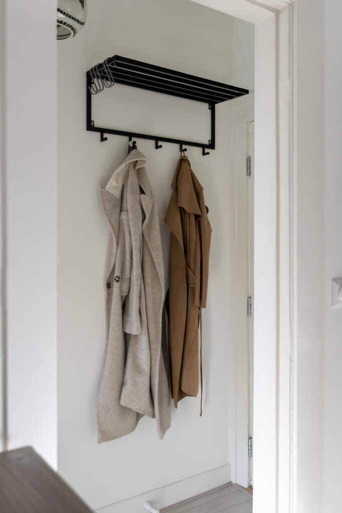Coats hanging on black wall hooks in hallway.