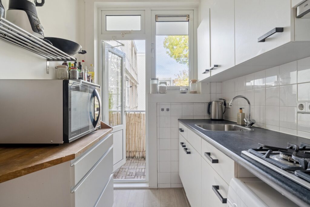 Modern kitchen with appliances and balcony view.